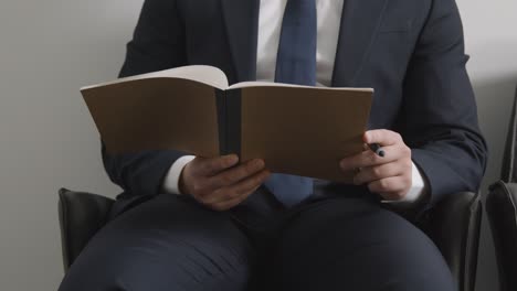 close up of male candidate wearing suit in office checking notes before job interview