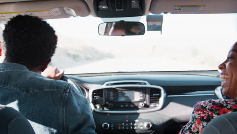 young black couple dancing in car as they drive, back view