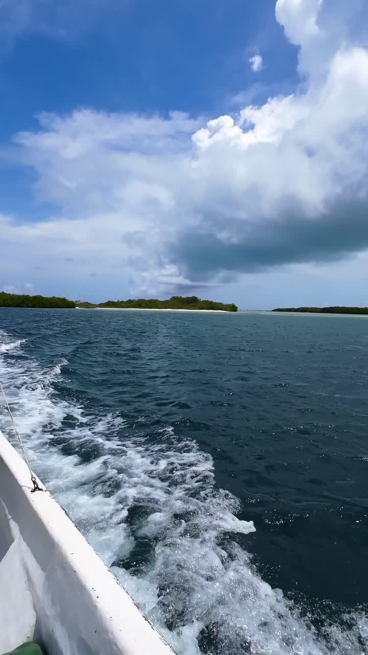 Barco dejando una estela mientras navega pasando por islas tropicales