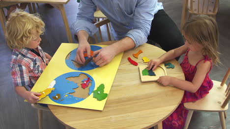 maestro y alumnos usando formas de madera en la escuela montessori