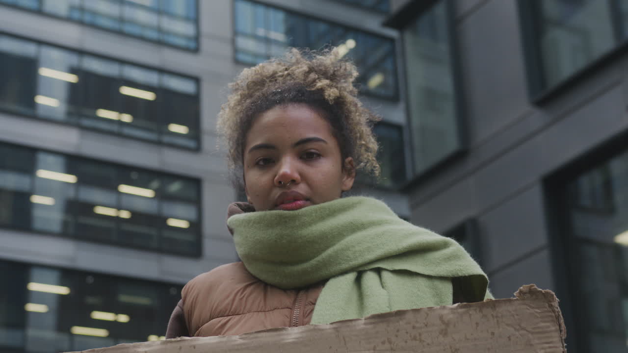 Young American Female Activist With A Placard Protesting Against Climate Change While Looking At Camera