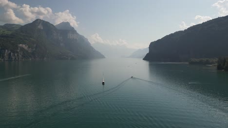 multiple boats on massive lake creating a passage between two great mountains some of them moving some are anchored bright pure day even the clouds creating and pointing towards the way through nice