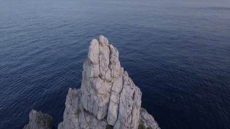 drone crane jib shot of ibiza's iconic rock benirrás starting with a close up and revealing why people call it 'the hand of god' 4k prores