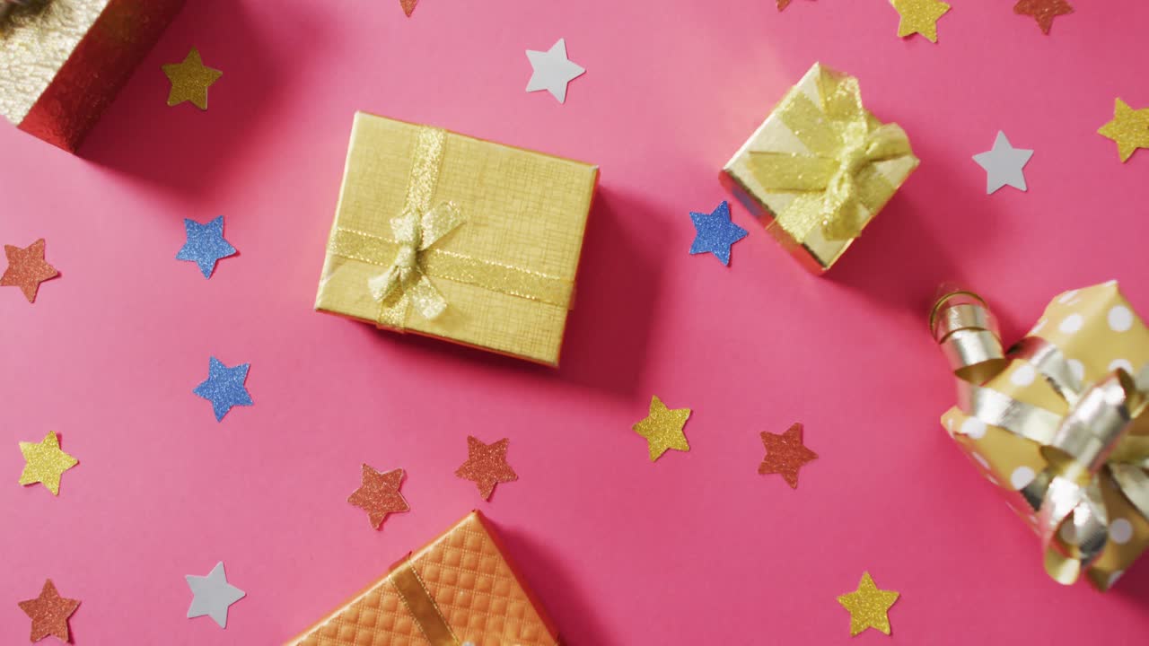 Video of wrapped presents and colourful stars on pink background