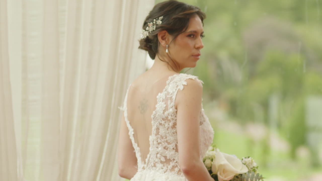 Medium shot of a bride walking with a bouquet of flowers, wearing a lace dress as she heads to the ceremony.
