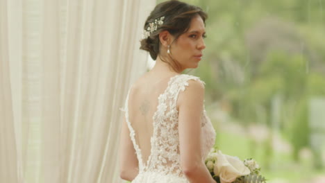 medium shot of a bride walking with a bouquet of flowers, wearing a lace dress as she heads to the ceremony.