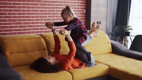 Mother-lifting-girl-in-air-on-her-ankles-at-home