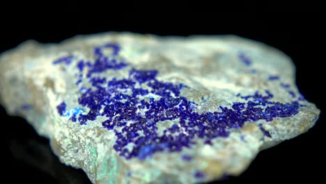 la rotación sin problemas de un mineral azul (azurita) frente a un fondo negro