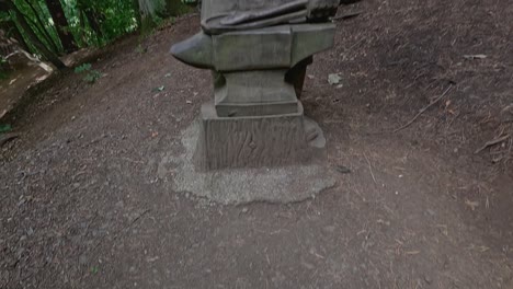 wooden statue of blacksmith in forest setting