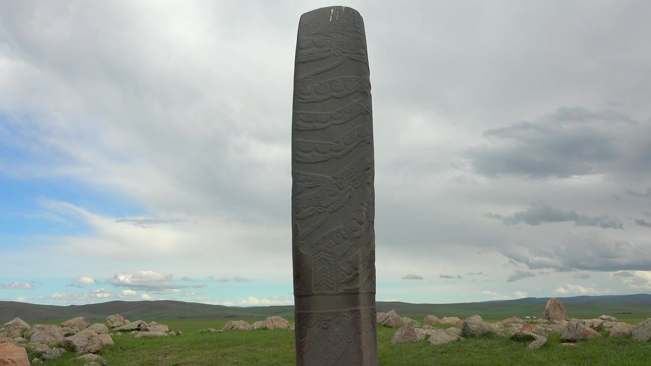 Gammel stenstele står på en stor grøn mark.