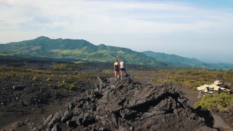 drone aerial shot flying over two girls standing on a rock, observing beautiful landscape with mountains in guatemala