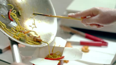 cu cook shifts the noodles with vegetables into the packaging for further delivery