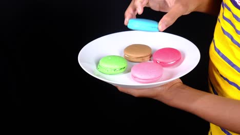 hand holding a plate of colorful macarons