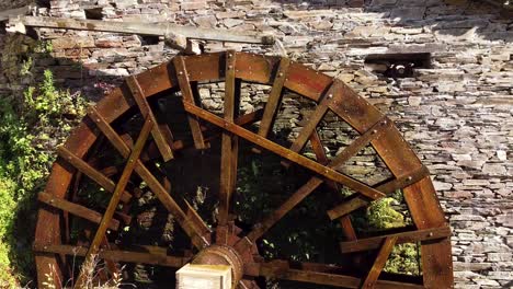 big water wheel rotating fast, attached to an old stone house