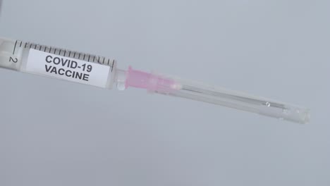 la mano de un médico con guante pone la aguja en la jeringa para la vacuna contra el virus de la corona, toma de cerca