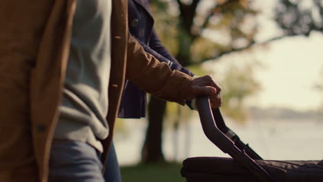 parents hands pushing carriage walking park closeup. unconditional love concept.