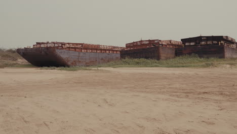 rusting barges left ashore: abandoned industrial vessels in a deserted landscape. industrial decline, environmental impact, and the passage of time. river drought