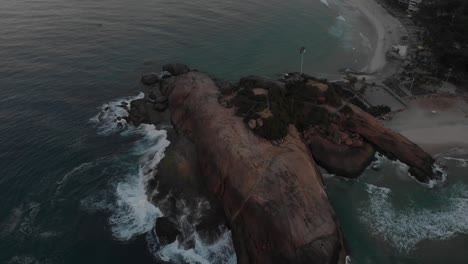 Aerial-pan-around-the-Arpoador-rock-in-Rio-de-Janeiro-revealing-the-sunrise-over-Copacabana-fort-and-Sugarloaf-mountain-in-the-background