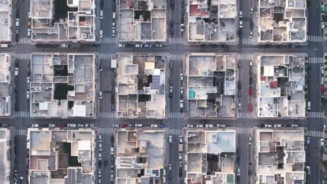 Top-down-static-aerial-footage-of-buildings-and-cars-driving-through-the-town-of-Monopoli,-Italy