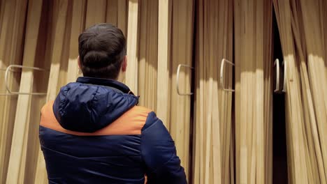 un joven elige vigas de madera en una tienda de materiales de construcción