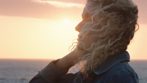 Primer-Plano-Retrato-De-Una-Hermosa-Mujer-Rubia-Disfrutando-De-La-Tranquila-Playa-Al-Atardecer-Contemplando-Un-Viaje-Explorando-La-Espiritualidad-Sintiendo-Libertad-Con-El-Viento-Soplando-El-Pelo