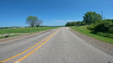 pov - driving on a park road with wooden barricades past wetlands and trees iowa on a bright summer day