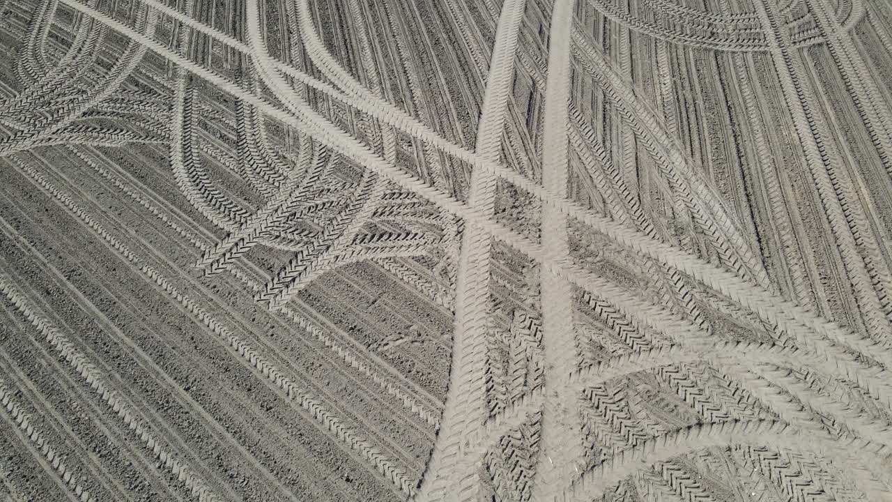 Drone shot of tracks in a sand field.