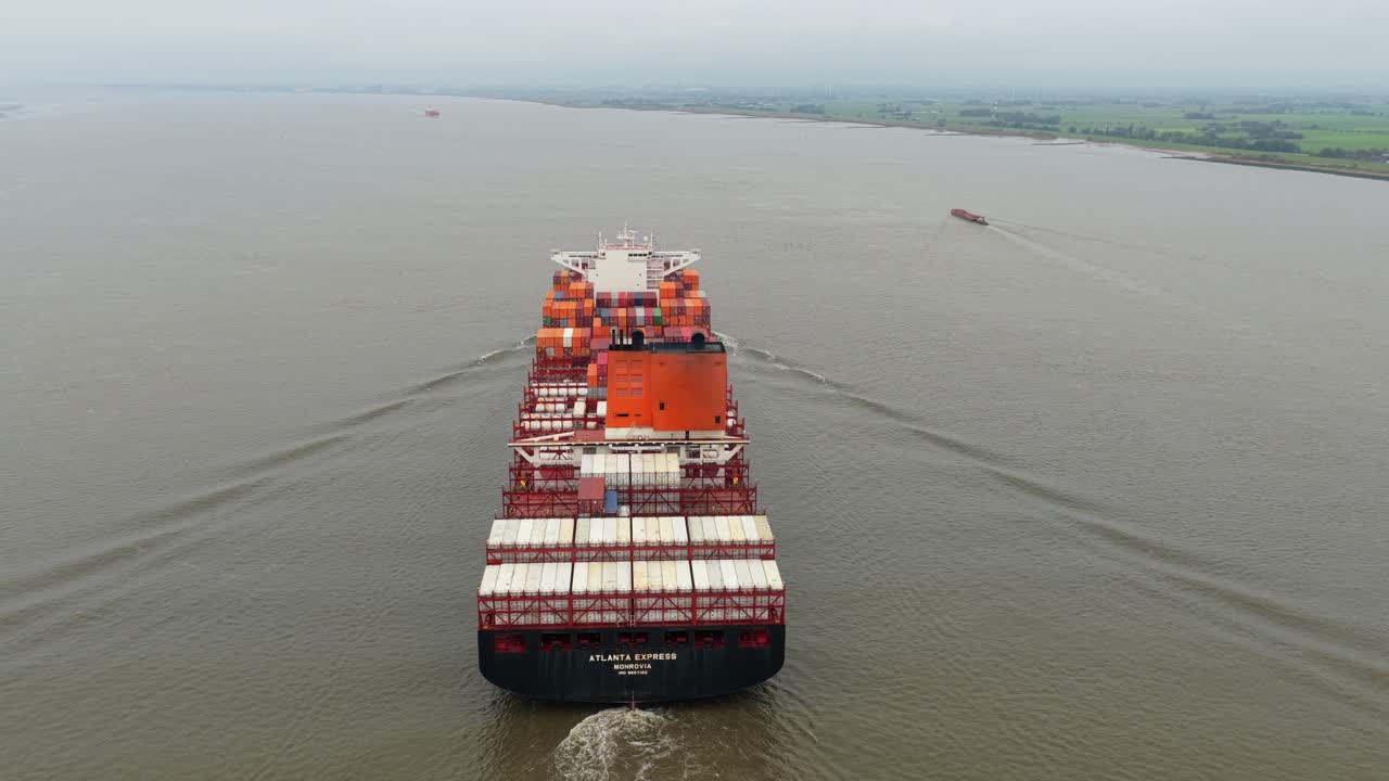 Vista aérea de un carguero saliendo del puerto con contenedores para exportación global.