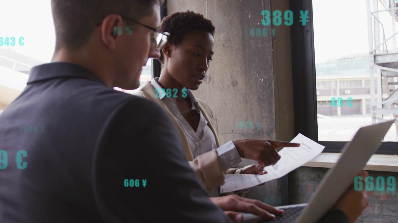 Woman pointing triggers turquoise numbers while colleagues checking papers and updating laptop