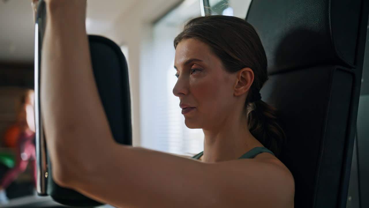 Portrait woman training arms muscles on sport machine at strength workout