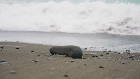 Schaumige-Meereswelle,-Die-Auf-Felsen-Und-Schwarzem-Sand-Kracht