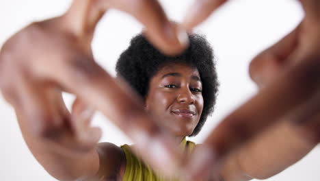 portrait of a smiling woman making a heart shape with her hands