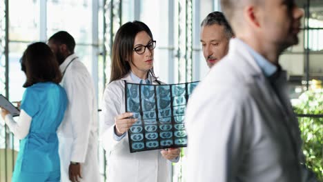 caucasian couple of male and female doctors standing in hospital, talking and looking at x-ray