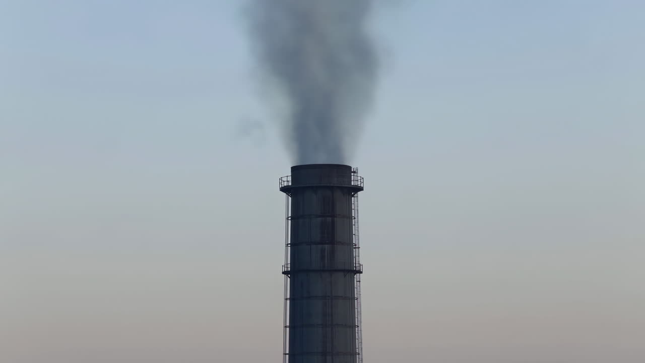 Ciminiera industriale che emette fumo denso nel cielo