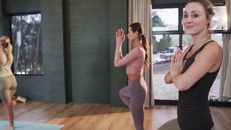 Mujeres-Diversas-Enfocadas-Estirándose-Juntas-En-Colchonetas-En-Clase-De-Yoga-Con-Entrenadora,-Cámara-Lenta