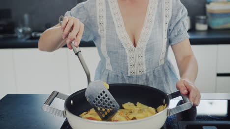 young housewife frying potatoes in a trendy modern kitchen at home