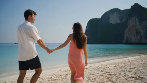 couple holding hands and walking on a tropical beach