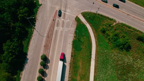 top down aerial of two red semi trucks and trailers stoppimg on a red light stop