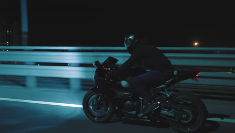 a man rides a sports motorcycle through the city at night