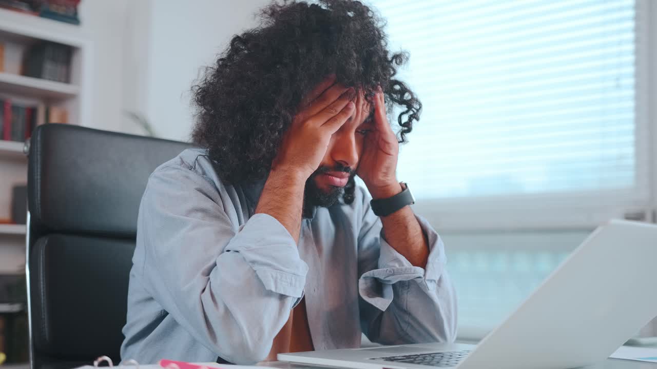 Young worried arabian man nervous waiting for letter in laptop sits in office