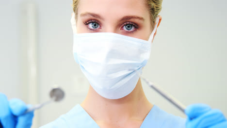 Portrait-of-female-nurse-holding-dental-tools