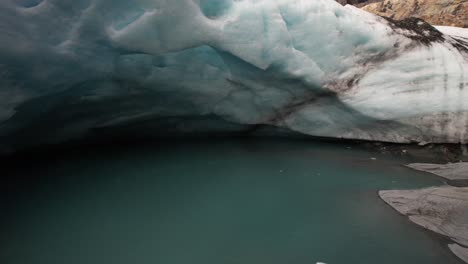 Unique-drone-from-ice-cave,-melting-glacier-into-river-in-high-mountains