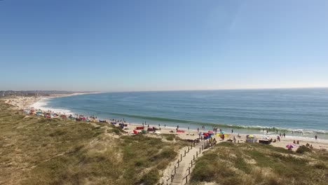 wooden walkway to the beach over dunes and people in the sea