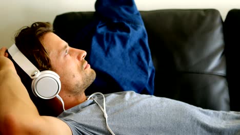 man listening music on headphones living room 4k