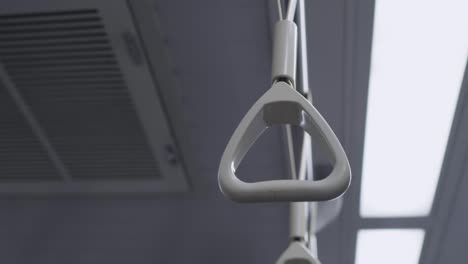 the hand ring  in the train carriage. the train is moving and the camera shakes. the subject is on the right. there are lights in the background.