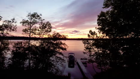 flying toward docked pontoon boat at sunset on reflective lake