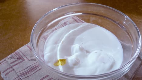 flocos de maíz amarillos crujientes en el cuenco para la mañana un delicioso desayuno con leche. cámara lenta con toma de seguimiento de rotación.