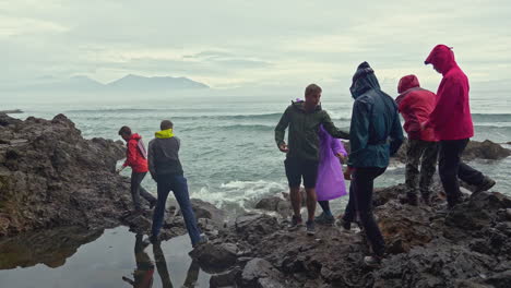 people on a rocky coastline during a stormy day