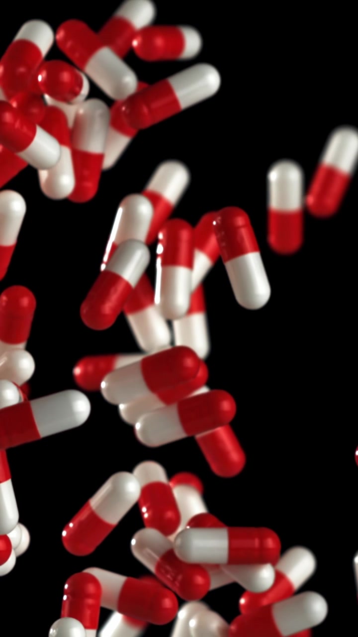 Red and White Medicine Capsules Falling in Slow Motion