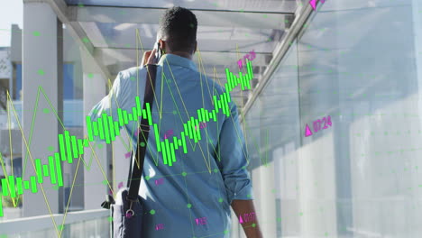 Animation-of-graphs-and-changing-numbers,-biracial-man-walking-with-trolley-bag-talking-on-cellphone